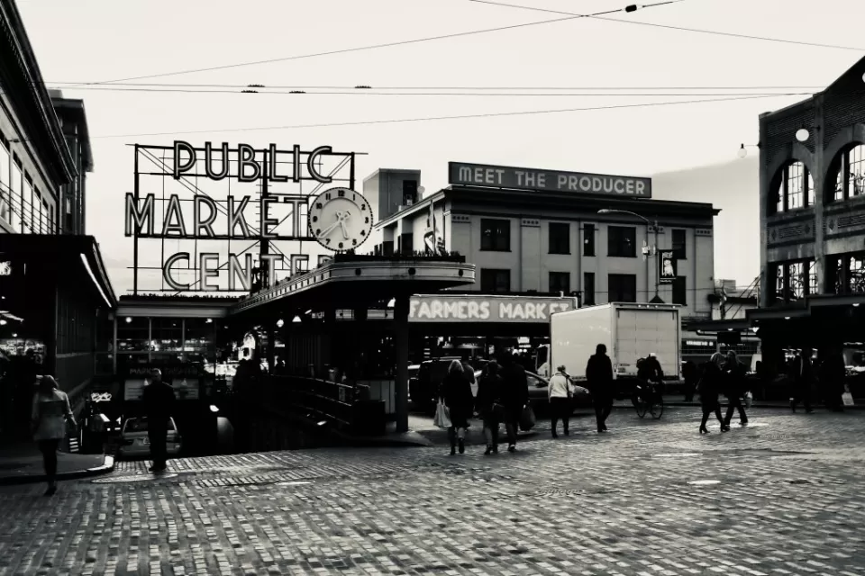 Black and white photo of Pike Place Market entrance in Seattle with "PUBLIC MARKET" and "Meet the producer" signs